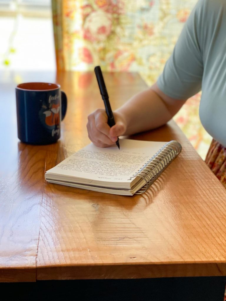 woman writing a letter with a fountain pen drinking a cup of coffee
